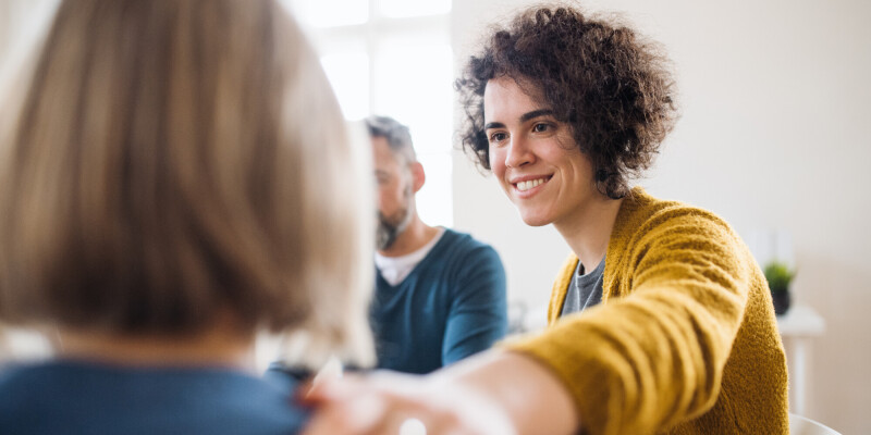 men women sitting circle group therapy supporting each other