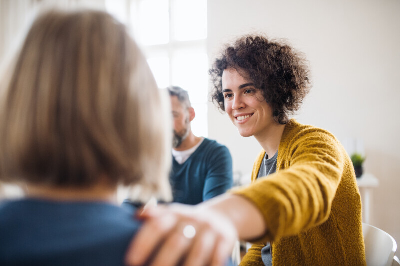 men women sitting circle group therapy supporting each other